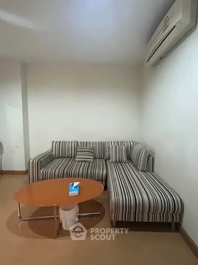 Cozy living room with striped sofa and air conditioning, perfect for relaxation.