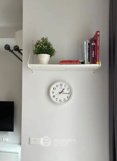 Modern living room with wall clock, shelf, and books for stylish decor.
