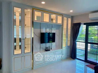 Elegant living room with built-in cabinets and modern TV setup, featuring large windows and natural light.