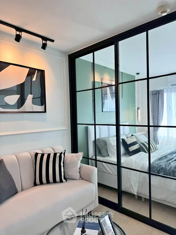 Modern apartment with stylish living room and cozy bedroom separated by glass partition.