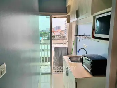 Compact kitchen with modern appliances and city view from balcony.