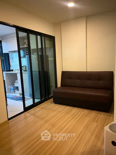 Modern apartment interior with sleek kitchen and cozy living area featuring a stylish brown sofa.