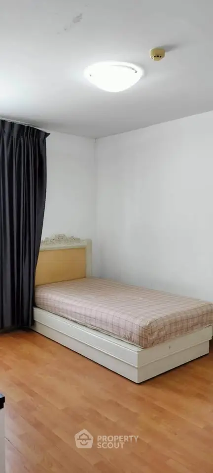 Cozy bedroom with single bed and wooden flooring, perfect for a minimalist lifestyle.