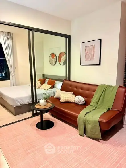 Modern living room with stylish decor and cozy bedroom view through glass partition.