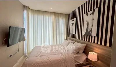 Cozy bedroom with modern decor and wall-mounted TV, perfect for relaxation.