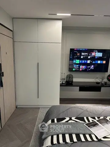 Modern bedroom with sleek wardrobe and wall-mounted TV, featuring stylish decor and cozy bedding.