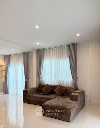 Spacious living room with plush brown sectional sofa and elegant curtains.