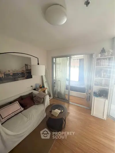 Cozy living room with wooden flooring and sliding glass doors leading to a bedroom.
