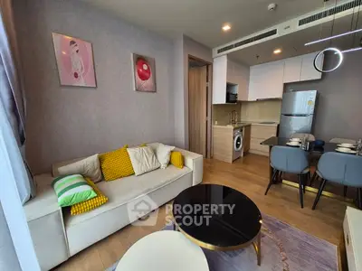 Modern living room with stylish decor and open kitchen layout, featuring cozy seating and dining area.
