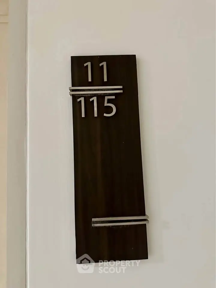 Modern apartment number sign with sleek design on white wall.