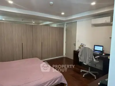 Spacious bedroom with modern decor and built-in wardrobe, featuring a cozy workspace and air conditioning.