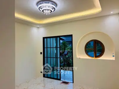 Elegant interior with modern lighting and unique window design, featuring a view of lush greenery outside.