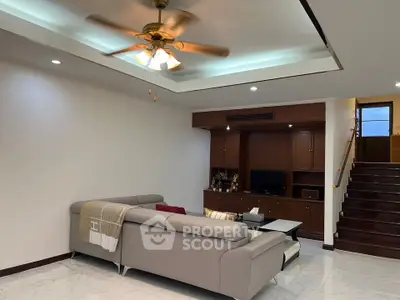 Spacious living room with modern sofa and ceiling fan, perfect for family gatherings.