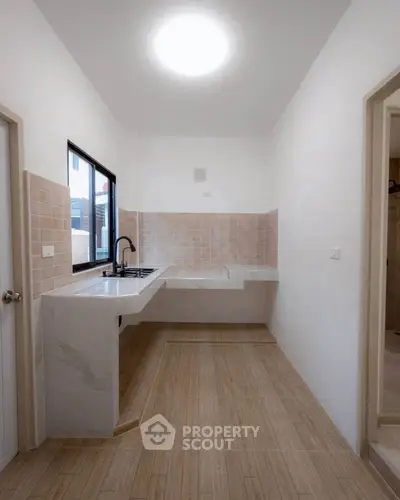 Modern kitchen with sleek countertops and ample natural light, featuring a minimalist design and tiled backsplash.