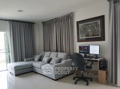 Modern living room with gray sofa and home office setup, perfect for work and relaxation.