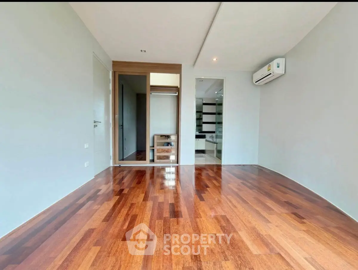 Spacious modern room with wooden flooring and air conditioning, ideal for versatile living space.