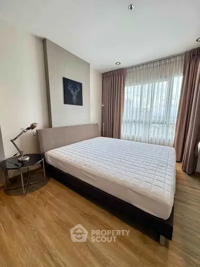 Modern bedroom with large window and stylish decor in a high-rise apartment.