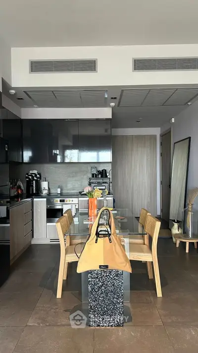 Modern kitchen with sleek cabinetry and dining area featuring stylish wooden chairs and table.