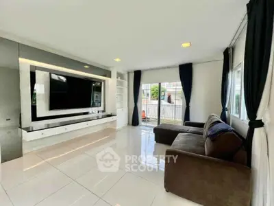 Spacious modern living room with large TV and elegant sofa, featuring floor-to-ceiling windows for natural light.