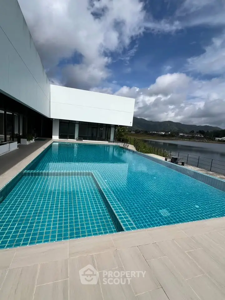 Luxurious modern building with stunning pool and scenic water view, perfect for relaxation and leisure.