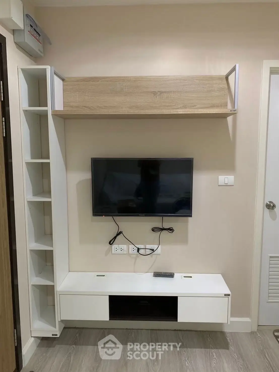 Modern living room with sleek TV unit and wooden shelving, perfect for stylish urban living.