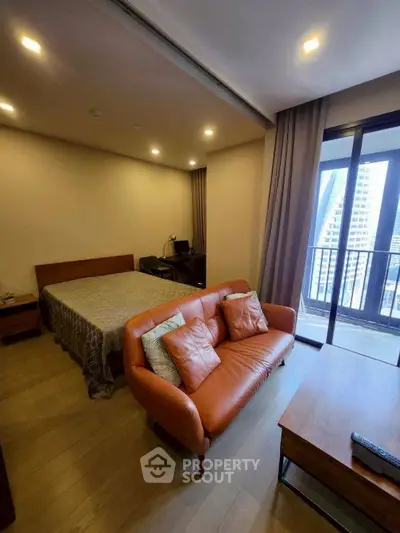 Modern studio apartment with cozy living area and balcony view in urban setting.