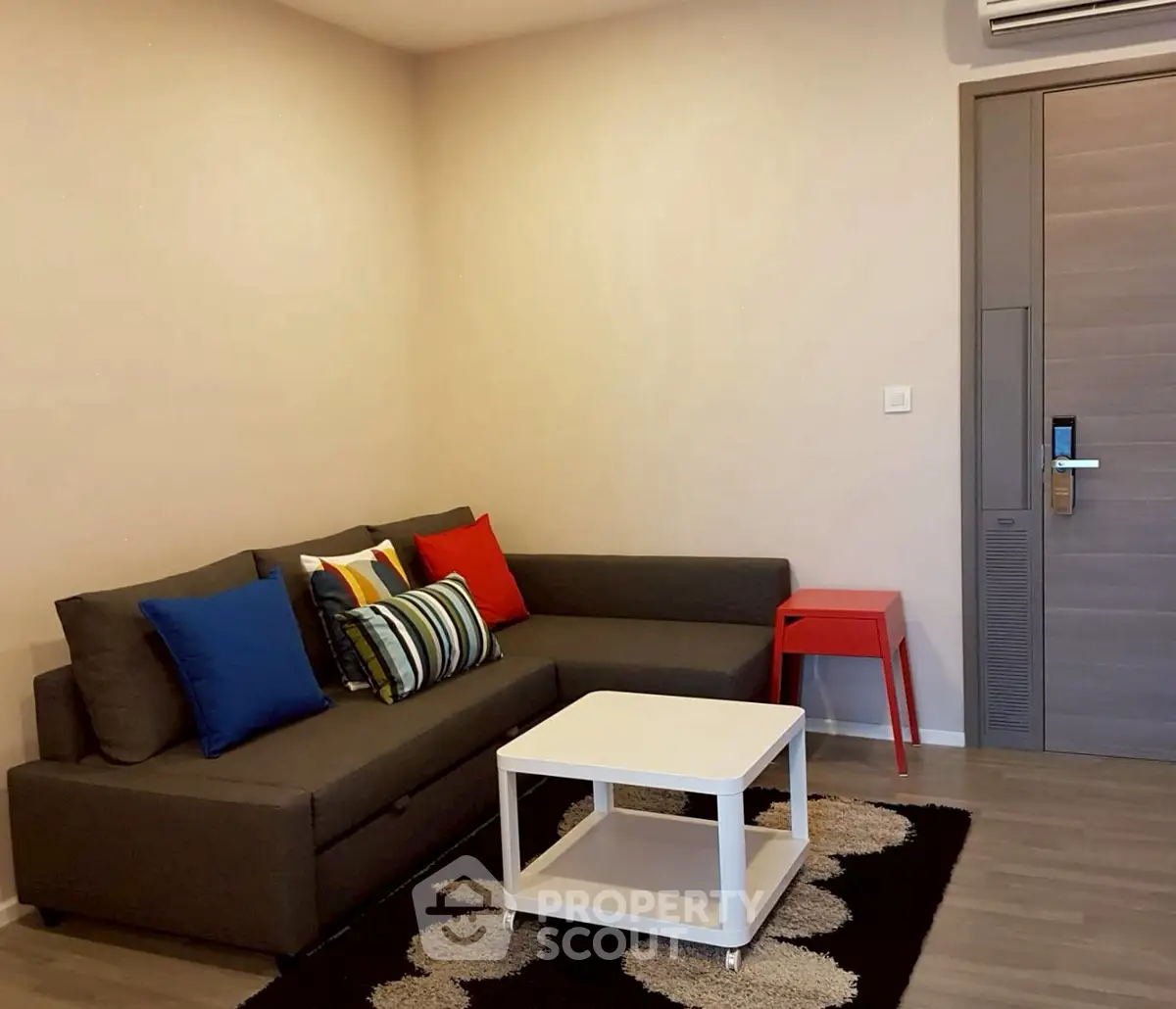 Modern living room with stylish sofa and colorful cushions, featuring a sleek coffee table and contemporary decor.