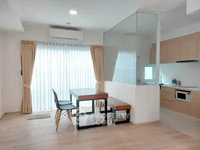Modern open-layout kitchen and dining area with natural light and sleek furnishings.