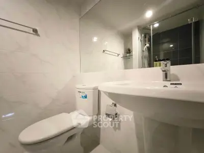 Modern bathroom with sleek white fixtures and elegant marble tiles.