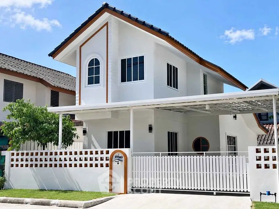 Charming two-story white house with a gated driveway and carport in a suburban neighborhood.