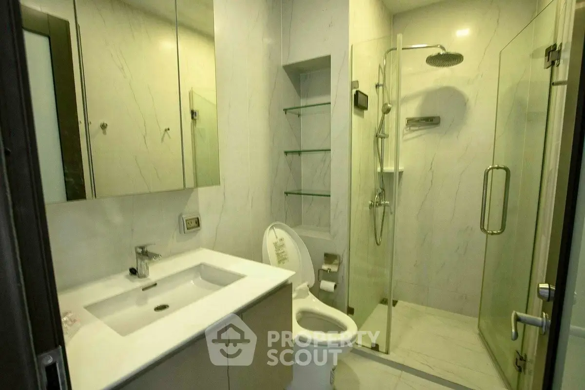Modern bathroom with glass shower and sleek fixtures in contemporary home.