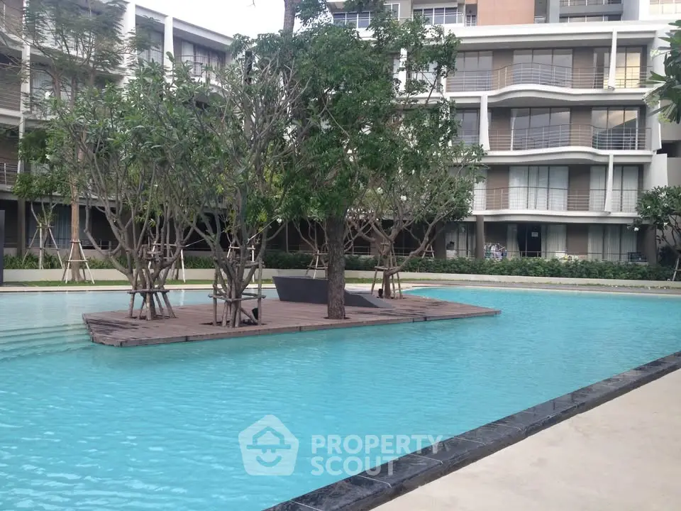Luxurious apartment complex with serene pool and lush greenery