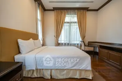 Elegant bedroom with luxurious furnishings and large window for natural light.