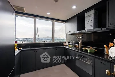 Modern kitchen with sleek black cabinetry and stunning bridge view through large windows.