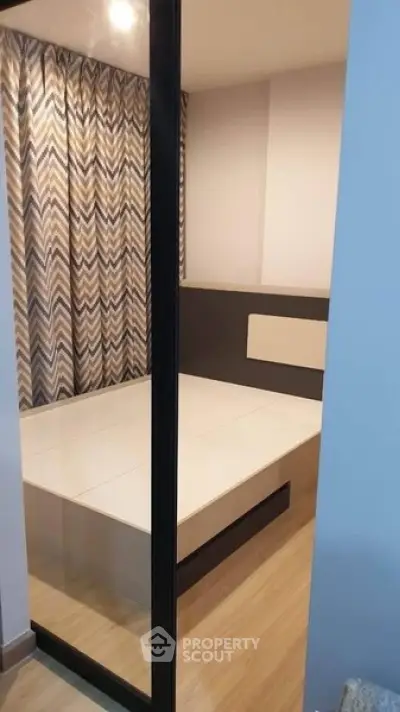 Modern bedroom with stylish chevron curtains and sleek wooden flooring.