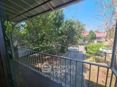 Charming balcony view with lush greenery and spacious driveway in serene neighborhood.