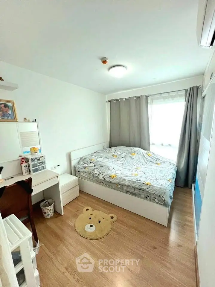 Cozy bedroom with wooden flooring and natural light, featuring a bed and study desk.