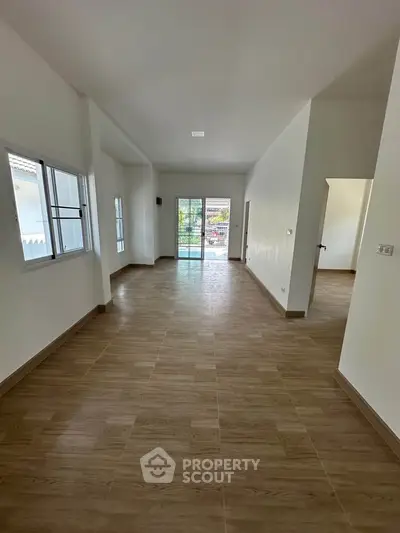 Spacious open-plan living room with large windows and sliding doors leading to a balcony.