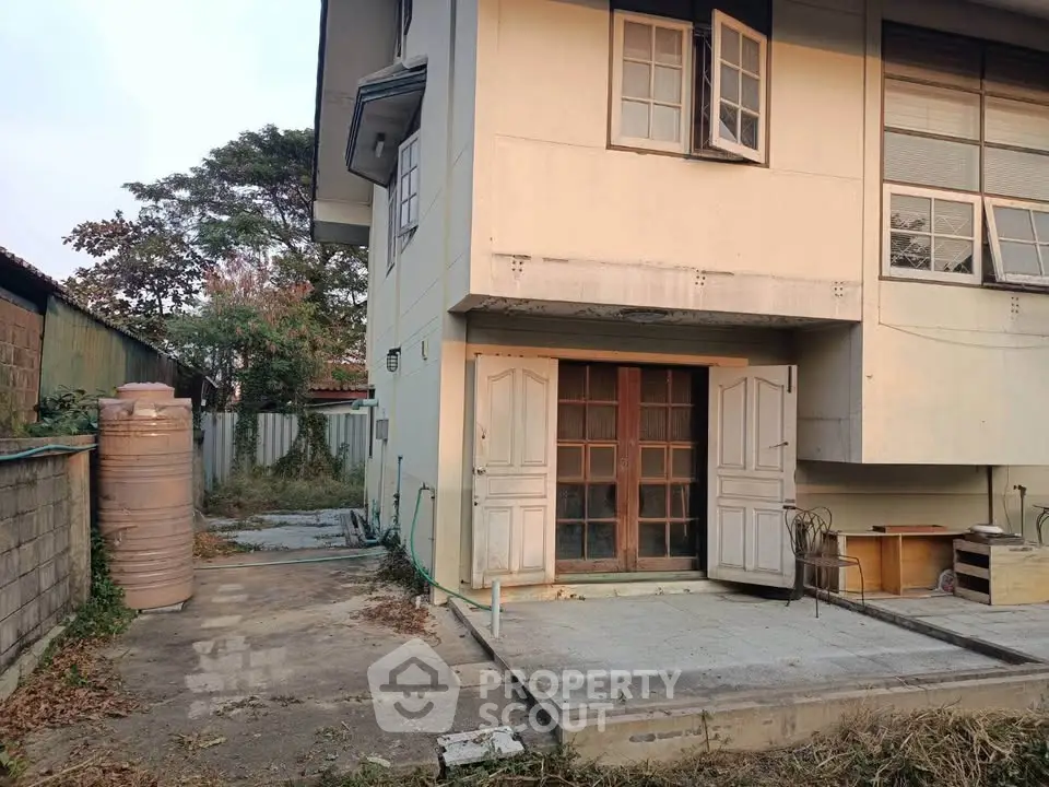 Charming two-story house with spacious outdoor area and rustic wooden doors, perfect for renovation enthusiasts.