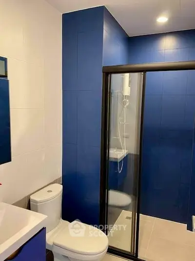 Modern bathroom with blue accent wall and glass shower enclosure
