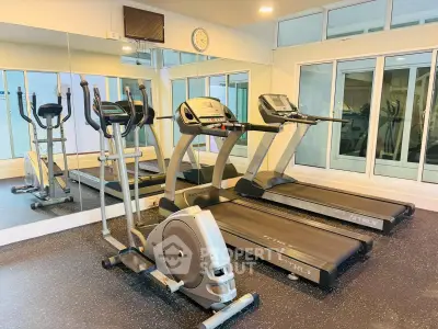 Modern gym with treadmills and exercise equipment in a bright, mirrored room.
