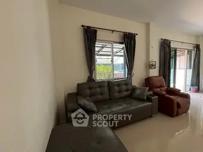 Spacious living room with modern leather sofa and large windows for natural light.