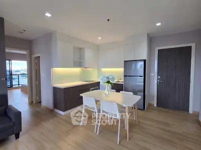 Modern open-layout kitchen with dining area and sleek appliances in a stylish apartment.