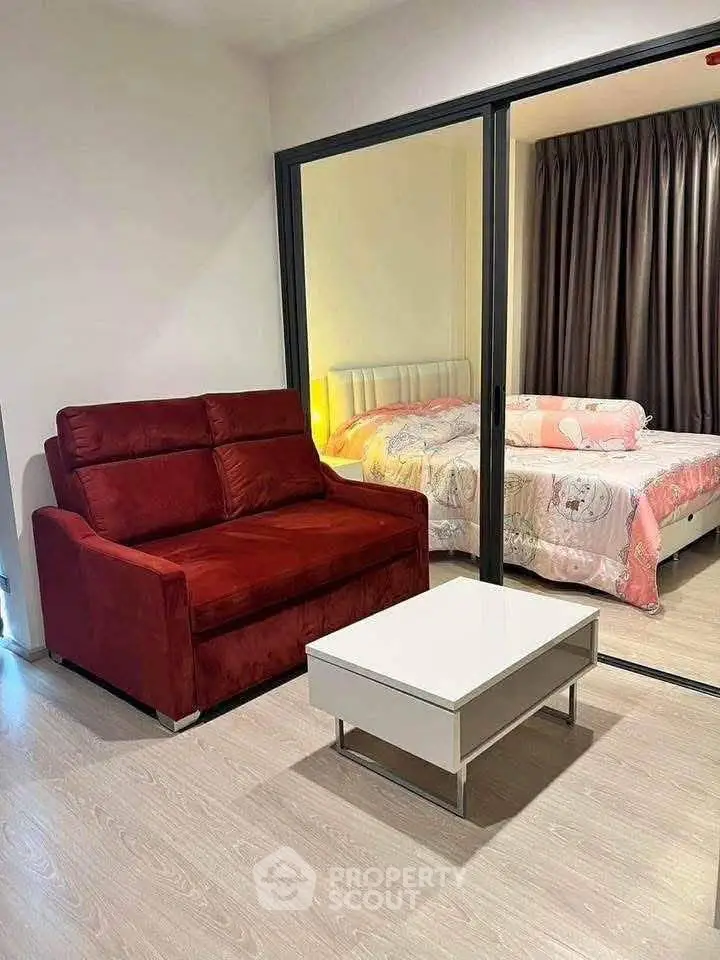 Modern apartment with cozy living area and stylish bedroom separated by glass partition.