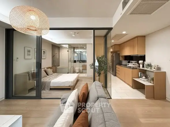 Modern open-plan living room with kitchen and bedroom, featuring sleek design and natural light.