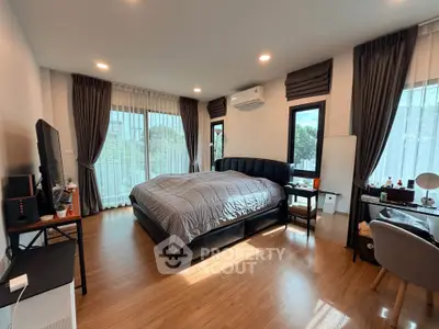 Spacious bedroom with modern decor and large windows offering natural light