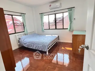 Bright bedroom with wooden flooring and large windows offering natural light.
