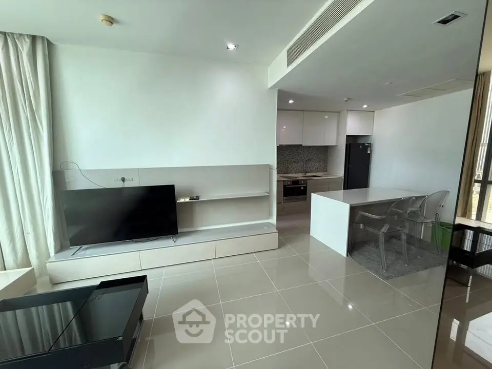 Modern open-plan living room with sleek kitchen and large TV, perfect for contemporary living.