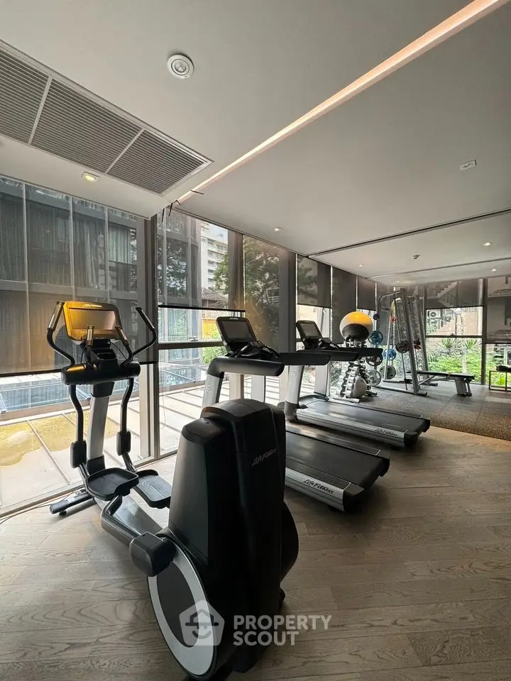 Modern gym with state-of-the-art equipment and large windows for natural light.