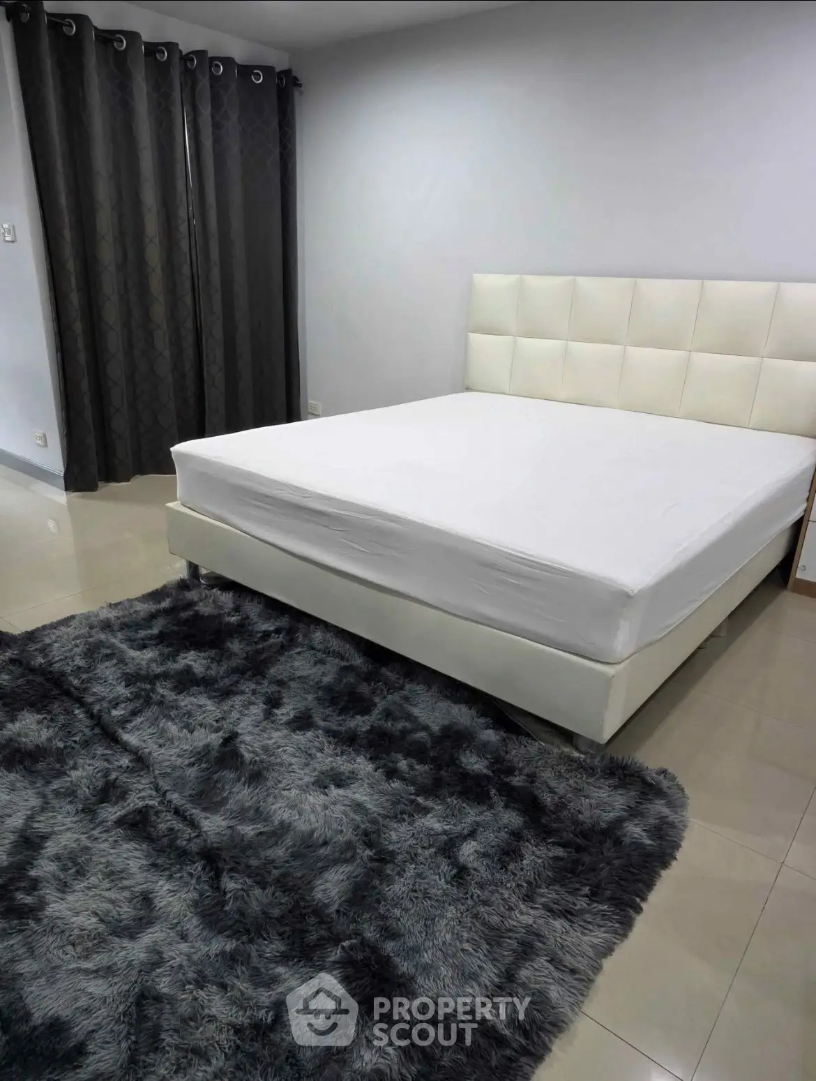 Spacious bedroom with modern white bed and plush gray rug